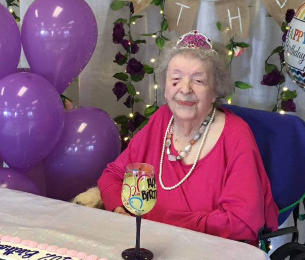 Elvira Giles with birthday cake and purple balloons