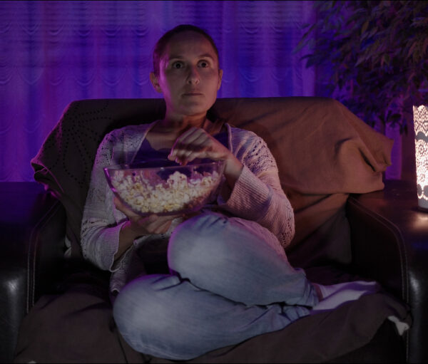 Woman relaxing at home with popcorn in front of the TV.