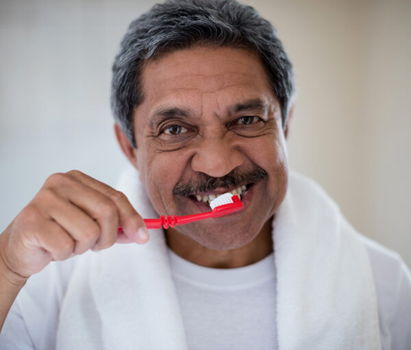 Portrait of senior man brushing teeth in bathroom at home