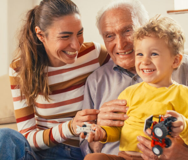 Portrait of a Small Family of a Mother, a Son and a Grandfather Watching TV Together in the Living Room. Family Generations Connecting and Bonding by Spending Time Together, Discussing and Having Fun