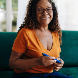 Black woman with diabetes uses a smart insulin pen to monitor and control her blood sugar levels, automatically recording the dose of insulin administered which helps manage the health condition.